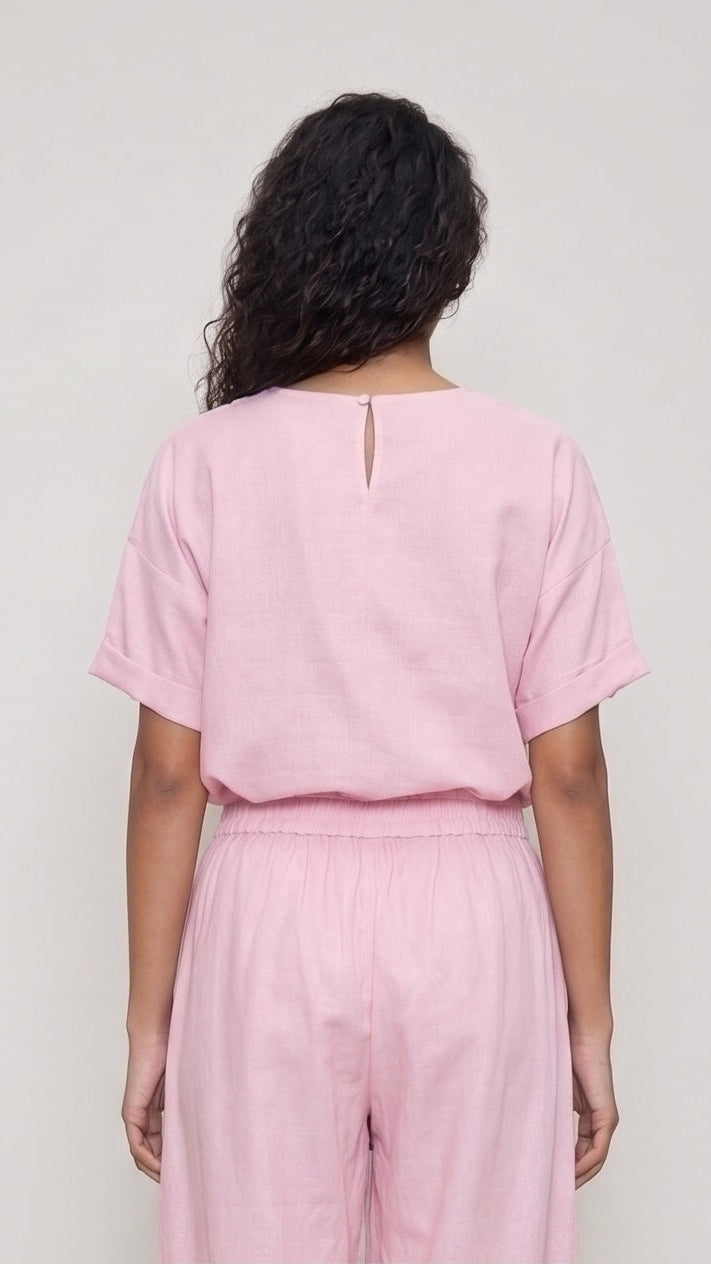 Person wearing a pink outfit against a plain background
