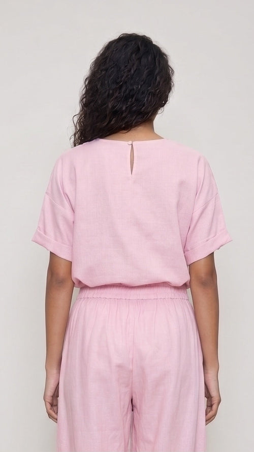 Person wearing a pink outfit against a plain background