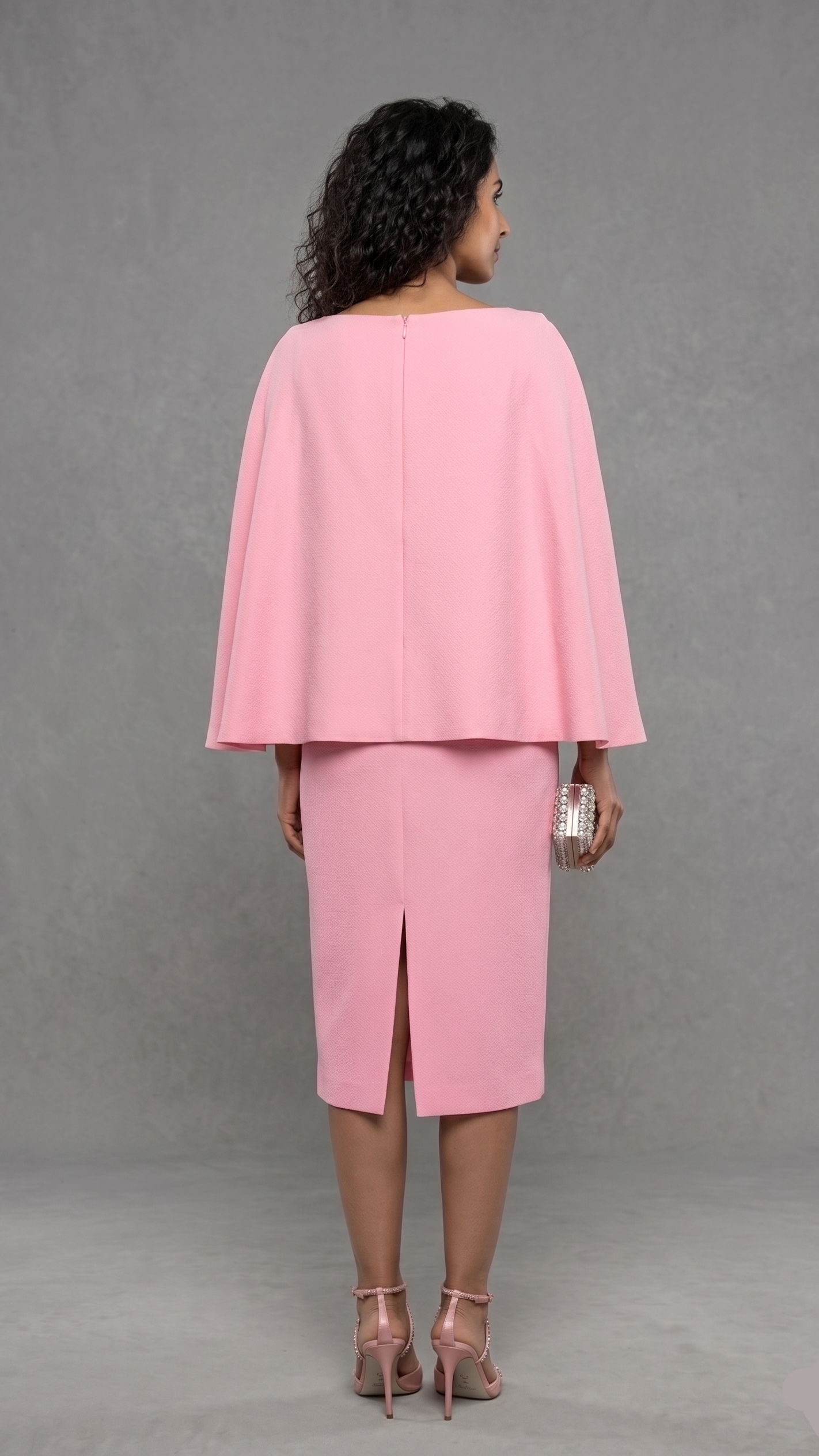 Woman wearing a pink cape and skirt set against a gray background