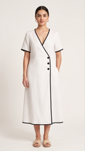 Woman wearing a white dress with black trim on a plain background