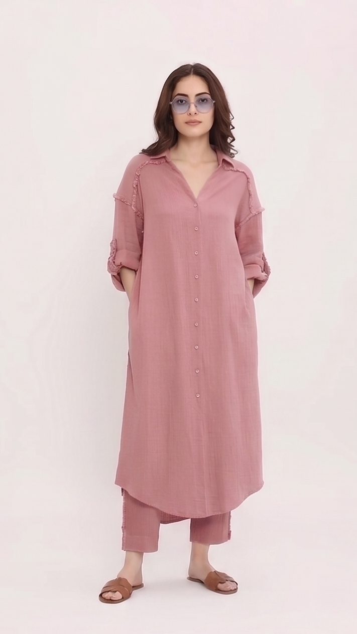 Woman wearing a long pink shirt and pants on a white background