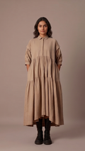 Woman wearing a beige dress against a plain background