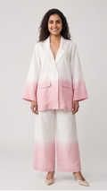 Woman wearing a baby-pink and white ombre blazer and pants on a light gray background