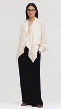 Woman wearing a beige blazer over a black dress on a white background