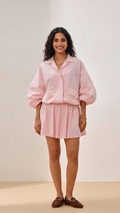 Woman wearing a pink outfit against a plain background