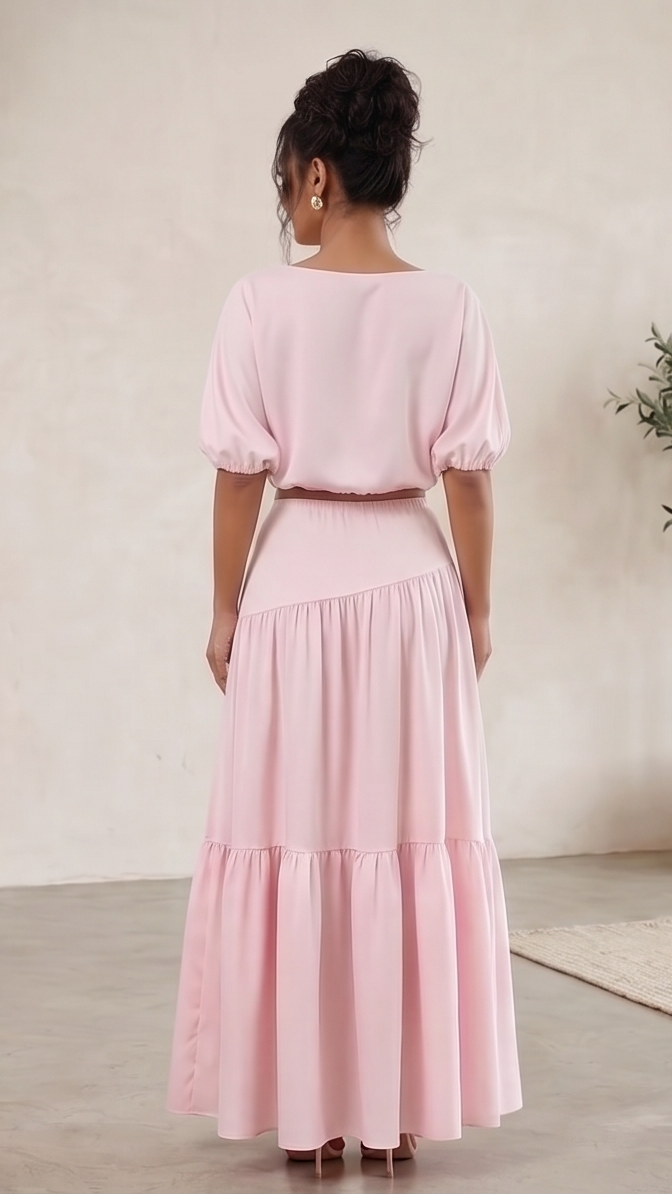 Person wearing a pink dress standing in a minimalistic room with a plant.