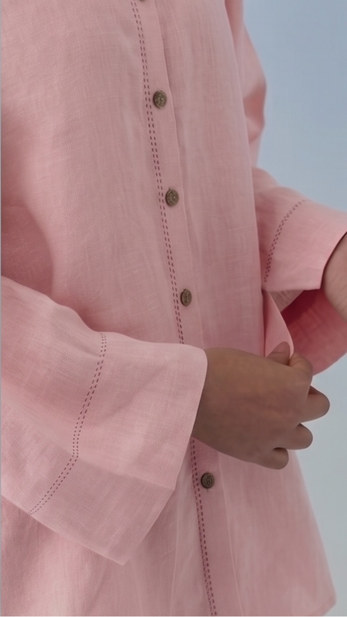 Close-up of a pink shirt with rolled-up sleeves and a blurred background