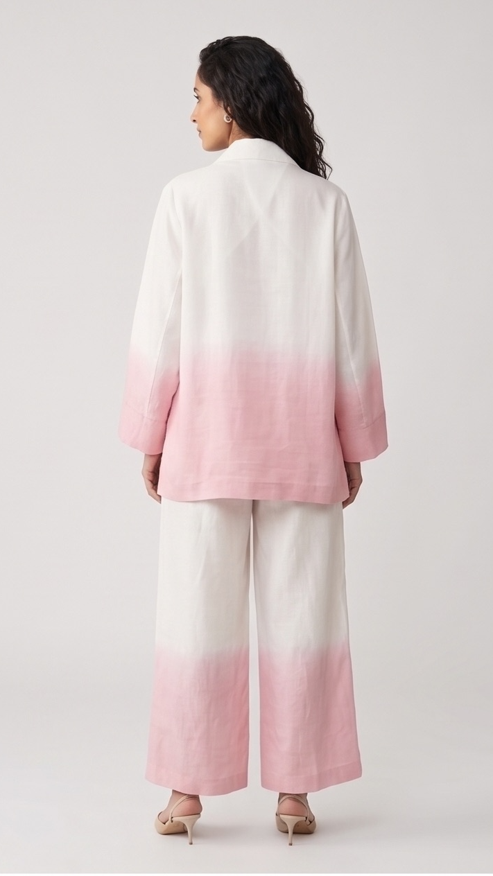 Woman wearing a baby-pink and white gradient coat with wide-leg pants on a light gray background