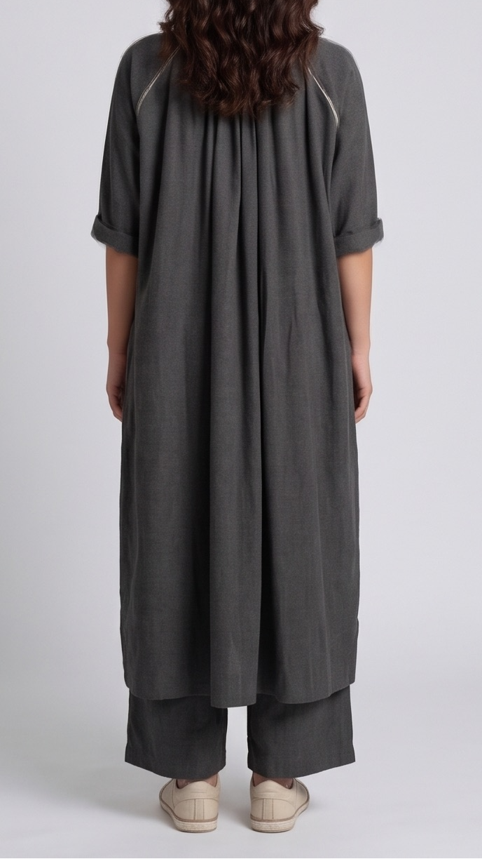 Person wearing a long dark gray dress with a plain background