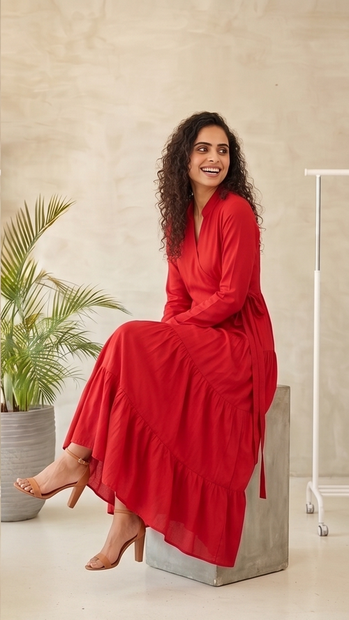Woman in a red dress sitting on a concrete block indoors.